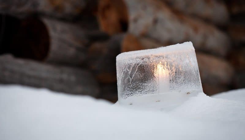 Lähikuva jäälyhdystä, jonka sisällä palaa kynttilä.
