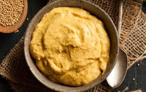 Kulhollinen sinappia ruokapöydällä.