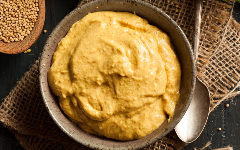 Kulhollinen sinappia ruokapöydällä.