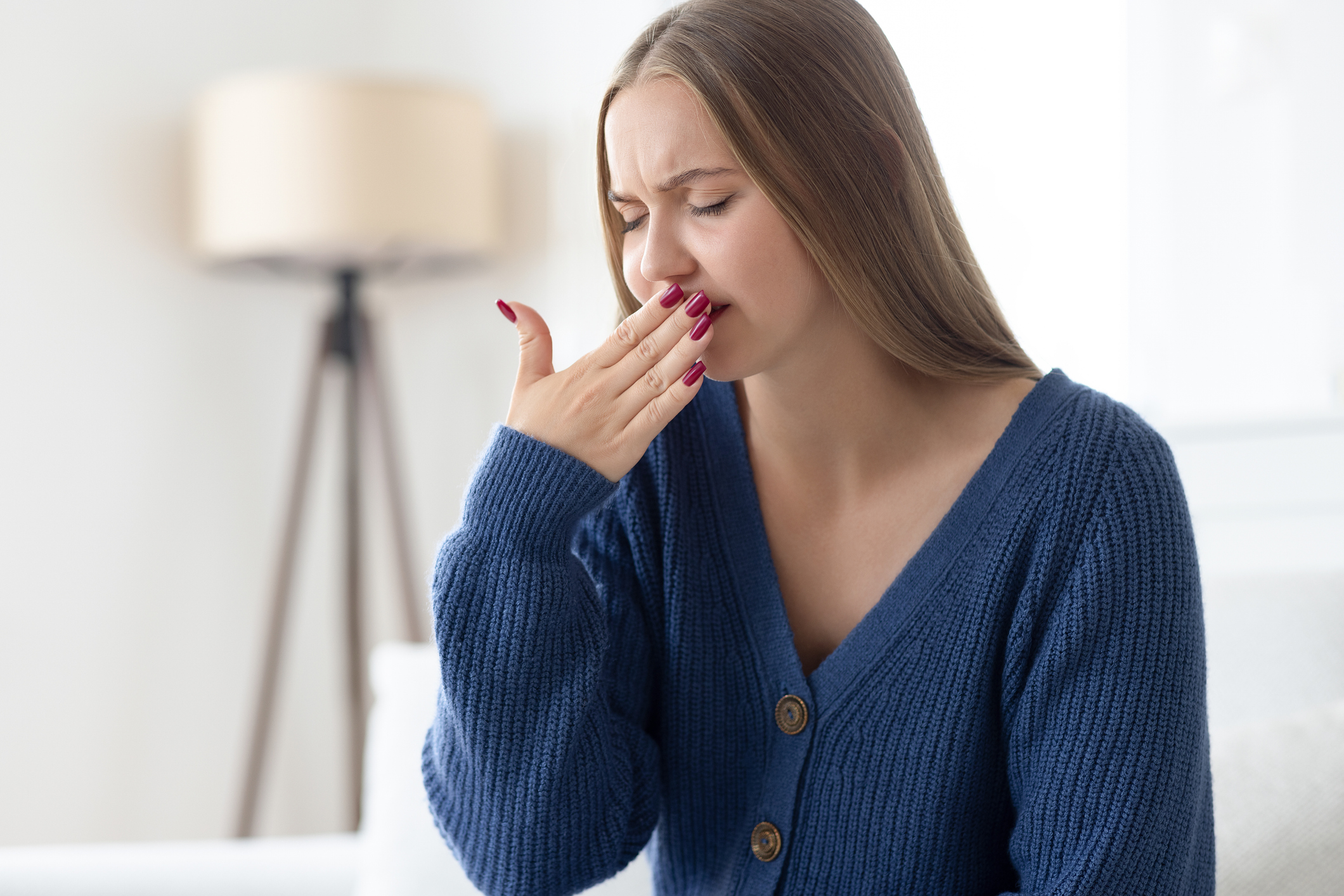 Nainen pitää kämmentä suunsa edessä peittääkseen hengityksensä hajua.