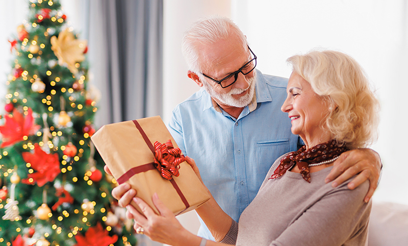 Harmaantunut pariskunta viettää yhdessä joulua iloisin mielin. Mies ojentaa naiselle ruskeaan paperiin käärityn joululahjan. Taustalla loistaa joulukuusi valoineen.