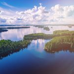 Ilmakuva sinisistä järvistä ja vihreistä metsistä kesäisessä Suomessa.